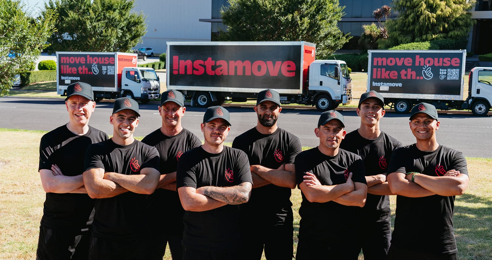 Instamove removalists loading labelled boxes stacked by the front door on moving day